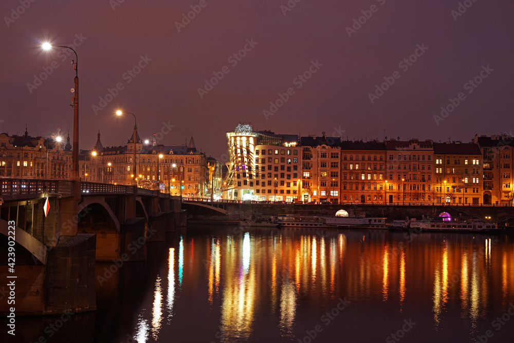 Historic bridge in Prague city center in night, lights mirroring in river, dancing house and Manes landmarks, Prague, Czech Republic