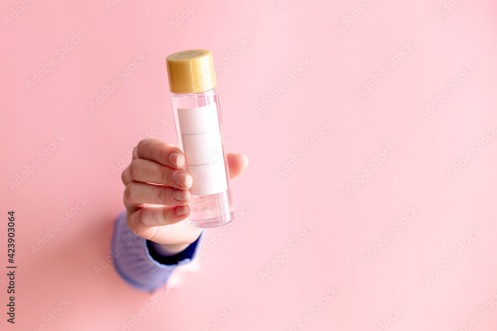 female hand hold cosmetic bottle on pink background. female hand hold cosmetic bottle on pink background.