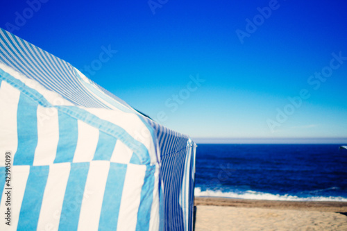 blue white striped tent on beach in front of sea