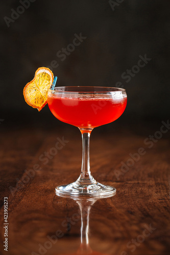 Red sweet cocktail on the wooden table with reflection