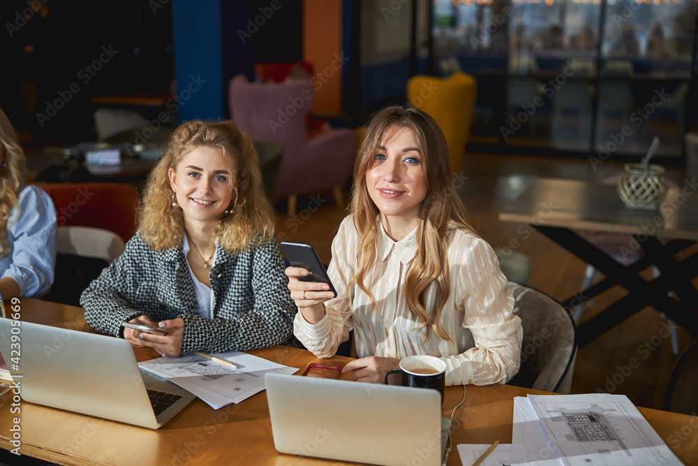Charming women using laptops and smartphones at work Charming women using laptops and smartphones at work
