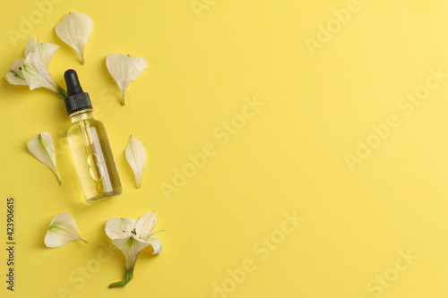 tender flatlay composition with oil, flowers on yellow background. Concept beauty natural vitamin cosmetic product, skin care, top view, copyspace