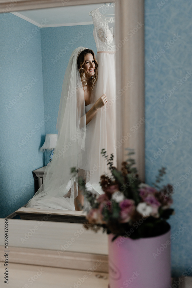 beautiful bride of European appearance hugs a wedding dress. joyful bride in a dressing gown is going to dress in the room beautiful bride of European appearance hugs a wedding dress. joyful bride in a dressing gown is going to dress in the room