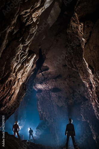 Speleologists wondering and admiring a gigantic cave chamber