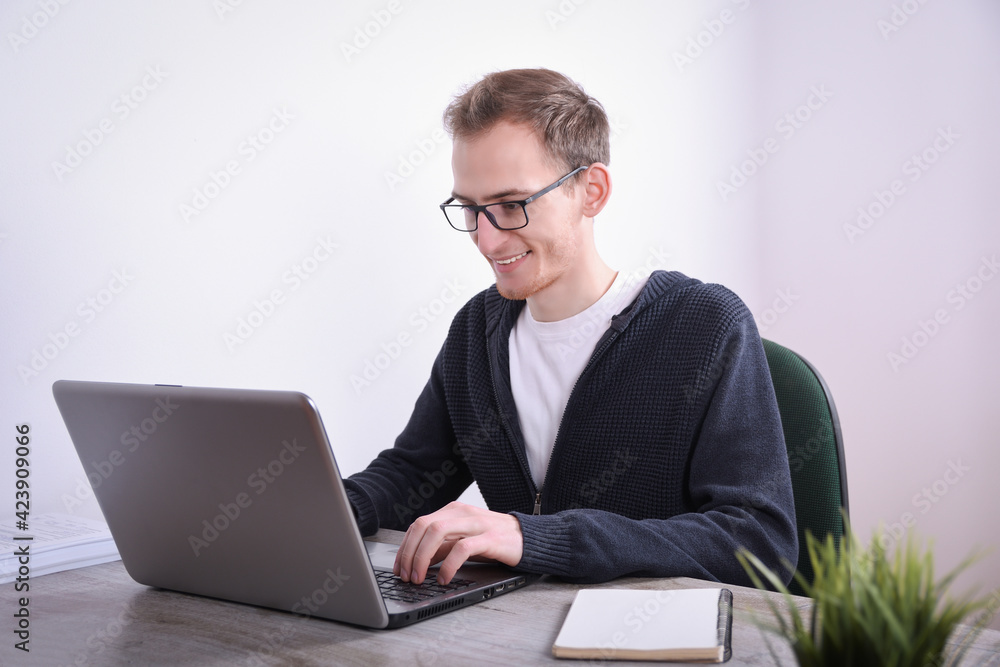 Portrait of young business man sitting at his desk desktop laptop technology in the office.Internet marketing, finance, business concept Portrait of young business man sitting at his desk desktop laptop technology in the office.Internet marketing, finance, business concept