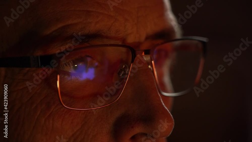 reflection in glasses of TV news. senior eye in glasses close-up, looks the news. Media deception. anxiety of people. photo