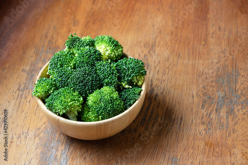 Fresh cut broccoli in wooden bowl on rustic wooden background
