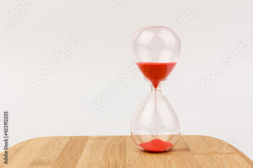 Crystal hourglass on wooden background as a concept of passing time for business term, urgency and outcome of time.