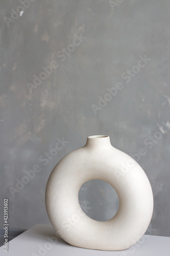 Stylish gray ceramic vase in the shape of a circle on the background of a concrete wall. Minimalism style in interior