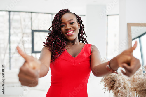 Free Download Magnificent young african woman in luxurious red dress in a luxury apartment. Beauty, fashion. Show thumb up to camera. - GFXLoad