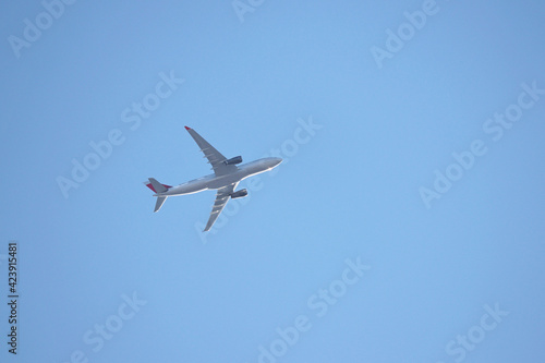 Airplane flying in the clear blue sky, bottom view. Commercial plane taking off and gaining altitude