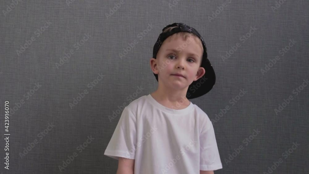 Little boy in white t-shirt and a black cap dances a breakdance hip-hop with his hands. Little boy in white t-shirt and a black cap dances a breakdance hip-hop with his hands.