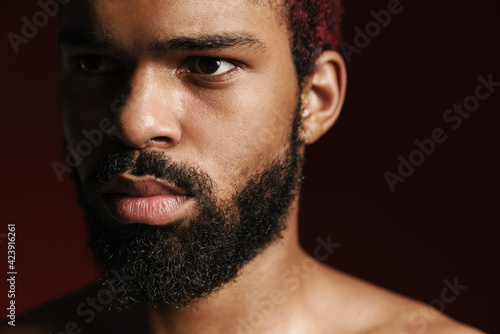 Black shirtless bearded man posing and looking aside