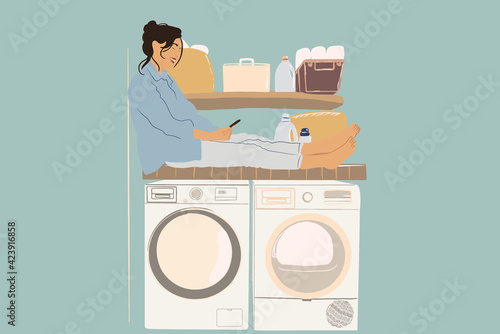 A pretty woman sitting in the washing machine and using a phone while waiting at the end of the wash cycle. Housewife doing routine. Baskets and detergents on the shelves. Vector illustration