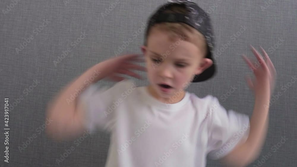 Little boy in white t-shirt and a black cap dances a breakdance hip-hop with his hands. Little boy in white t-shirt and a black cap dances a breakdance hip-hop with his hands.