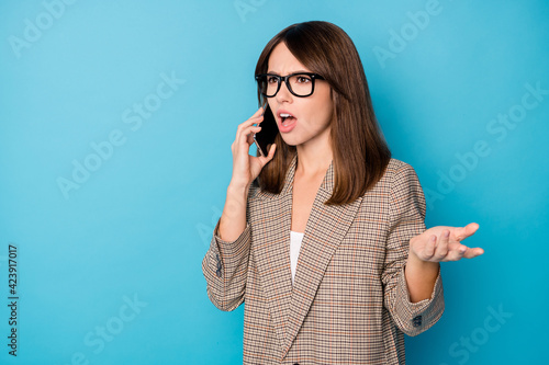 Photo portrait of unhappy woman talking on phone isolated on vivid blue colored background