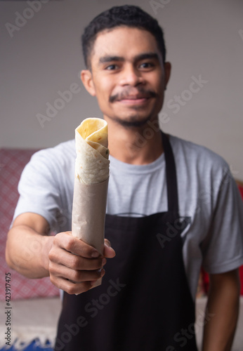 Photography Chef holding and serving roasted shawarma wrap or gyros in fast food restaurant