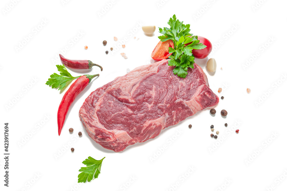 Marbled beef steak. Garnished with hot peppers, tomatoes, spices and herbs. View from above. White background. Isolated.