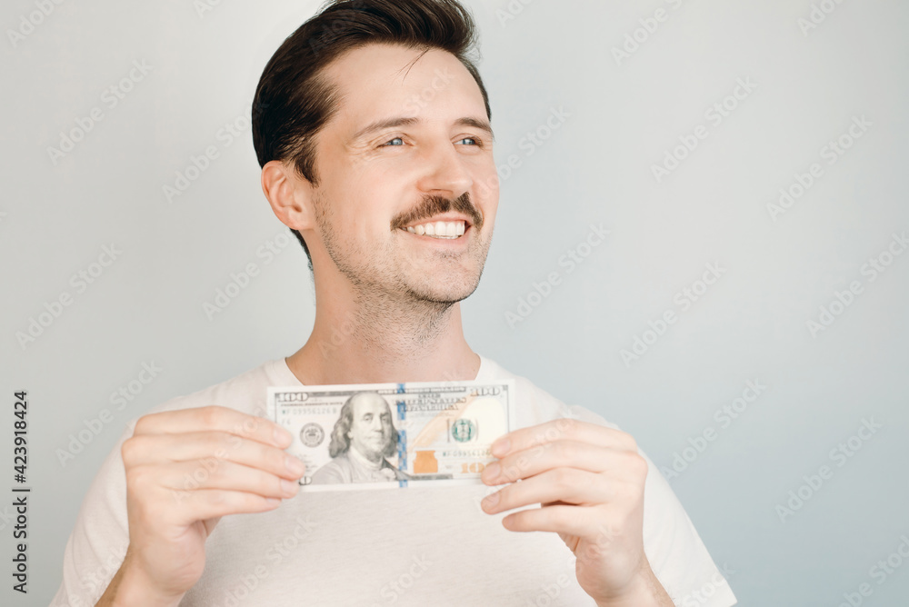 Smiling man holding one hundred dollar bill and rejoicing. Close-up of happy man indoors. Smiling man holding one hundred dollar bill and rejoicing. Close-up of happy man indoors.