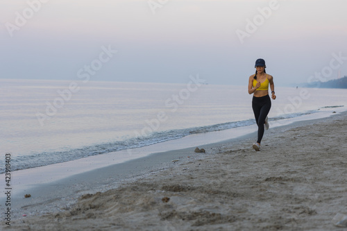 Asian female with yellow shirt running on the beach in the morning.