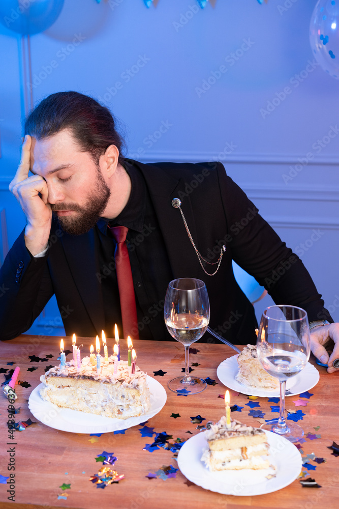 Upset man over birthday celebration in isolation. The man holds his hand to his head and looks down. Upset man over birthday celebration in isolation. The man holds his hand to his head and looks down.