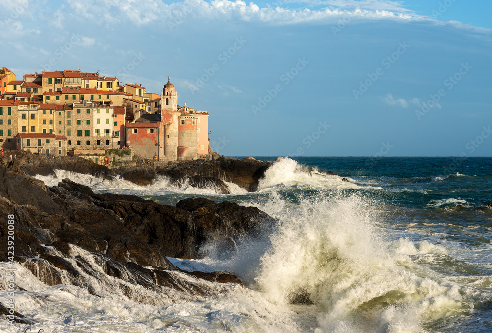 Rough Sea with big waves in front of the small and ancient Tellaro Village with the church of San Giorgio (St. George). Lerici municipality, Gulf of La Spezia, Liguria, Italy, Southern Europe.
