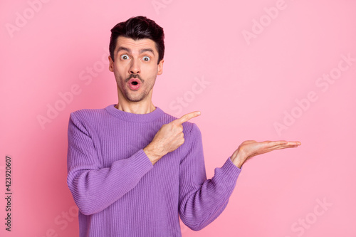 Photo of young man amazed shocked indicate finger product promo offer advert isolated over pink color background