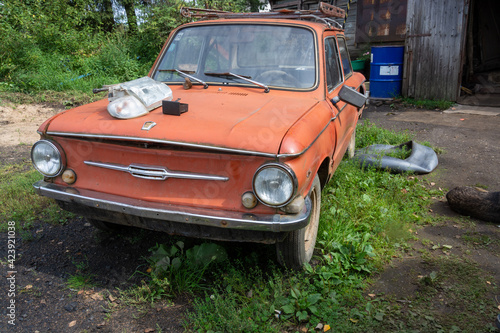 At the scrap metal reception point there is an old broken red Zaporozhets (ZAZ).  photo