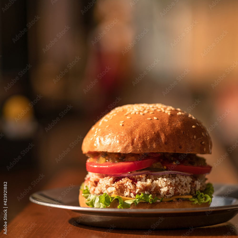 Fresh juicy hamburger with onion and lettuce on blurred background, close up shot. Nutritious dinner concept. Classic American Fast food snack or lunch. Soft focus. Fresh juicy hamburger with onion and lettuce on blurred background, close up shot. Nutritious dinner concept. Classic American Fast food snack or lunch. Soft focus.