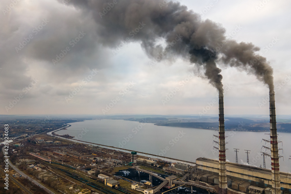 Aerial view of coal power plant high pipes with black smoke moving up polluting atmosphere.