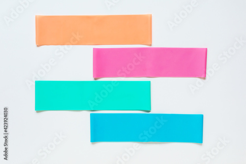 Colorful resistance fitness bands on white background, flat lay. Sports accessories. 