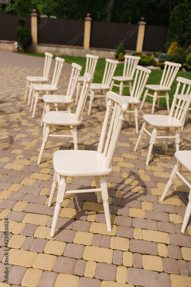 White wooden chairs stand in the yard. Chairs for a wedding ceremony