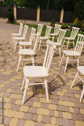 White wooden chairs stand in the yard. Chairs for a wedding ceremony