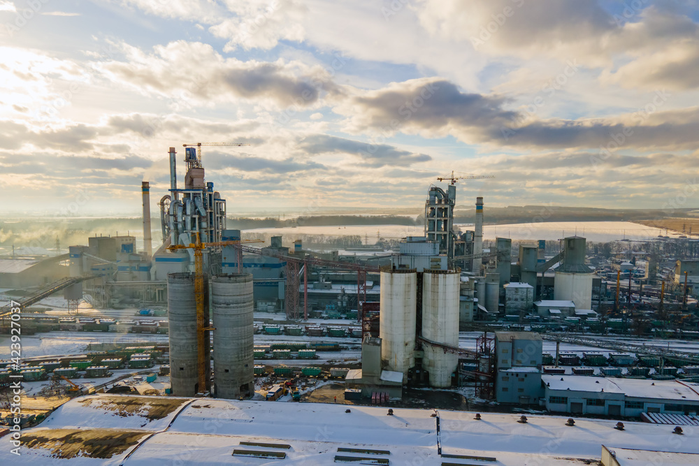 Fototapeta premium Aerial view of cement plant with high factory structure and tower crane at industrial production area.