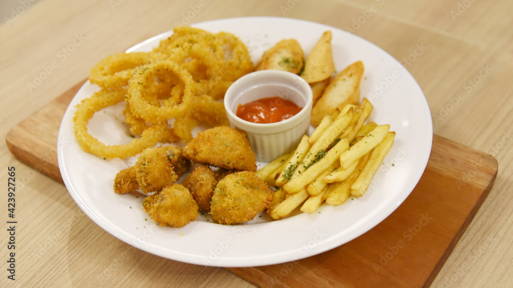 Onion ring mix with french fries, mushroom served on large plate Onion ring mix with french fries, mushroom served on large plate