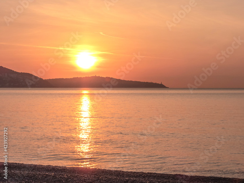 Lever de soleil et ciel de feu au-dessus du Cap Ferrat depuis une plage de la baie des anges à Nice sur la Côte d'Azur