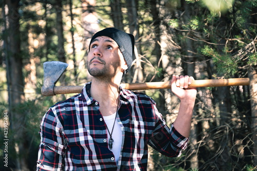 Lumberjack man with his ax on his shoulder in the forest
