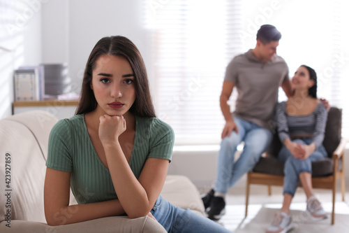 Unhappy woman feeling jealous while couple spending time together at home