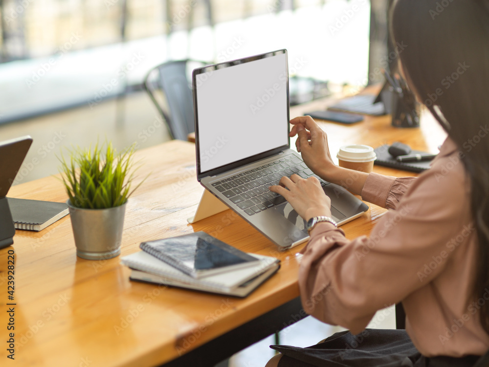 Fototapeta premium Businesswoman working with laptop and office supplies on wooden table in office room