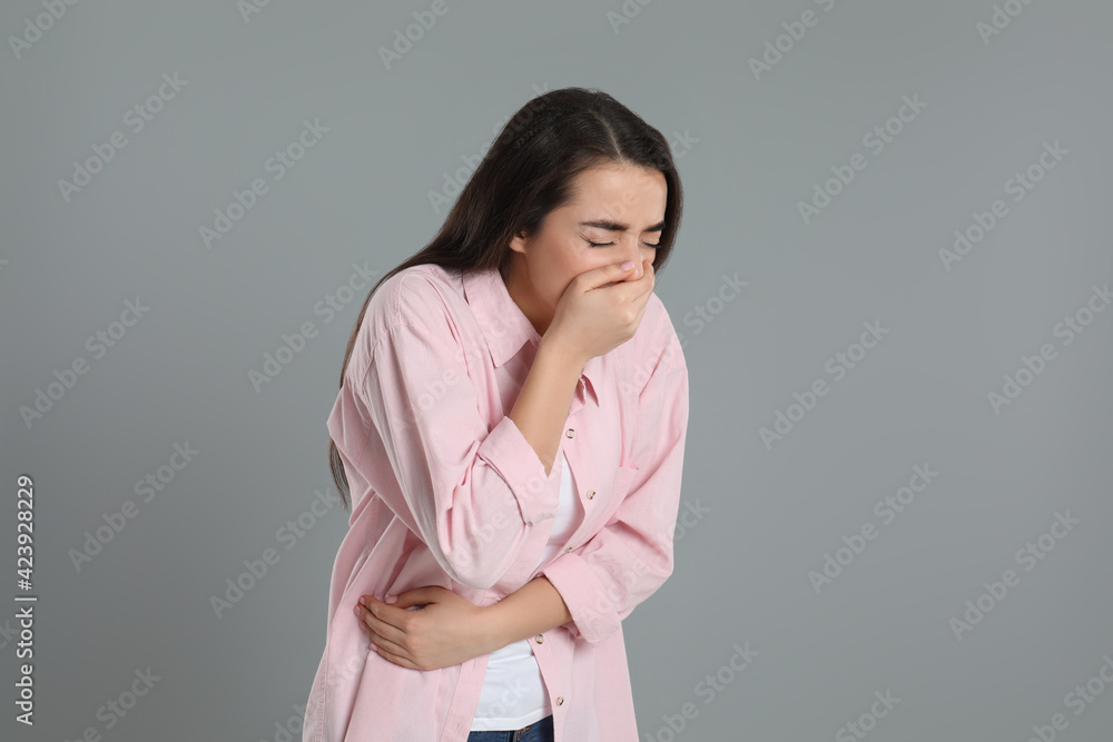 Young woman suffering from stomach ache and nausea on grey background. Food poisoning Young woman suffering from stomach ache and nausea on grey background. Food poisoning