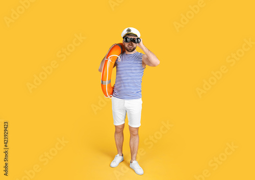 Sailor with binoculars and ring buoy on yellow background © New Africa