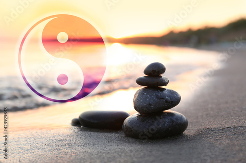 Canvas Print Stack of stones on sandy beach and Ying Yang symbol