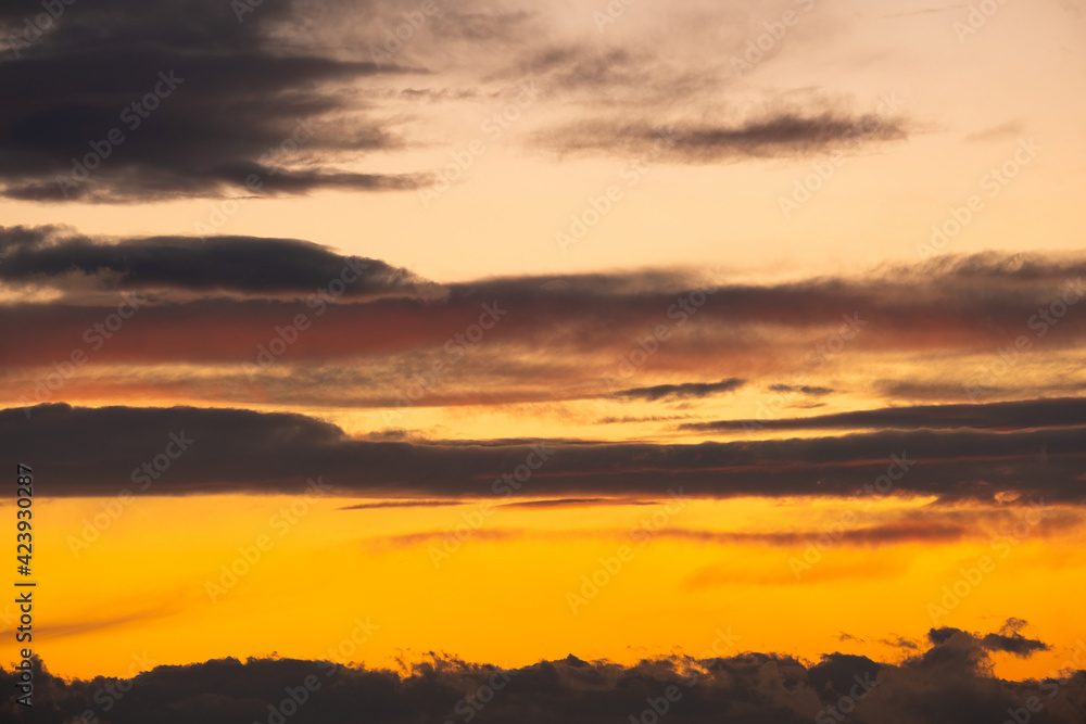 Dramatic sunset landscape with puffy clouds lit by orange setting sun and blue sky. Dramatic sunset landscape with puffy clouds lit by orange setting sun and blue sky.