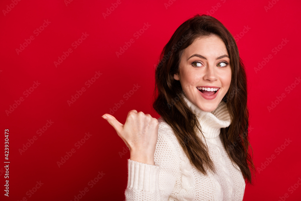 Photo of charming cute young woman dressed white sweater pointing thumb up looking empty space isolated red color background Photo of charming cute young woman dressed white sweater pointing thumb up looking empty space isolated red color background
