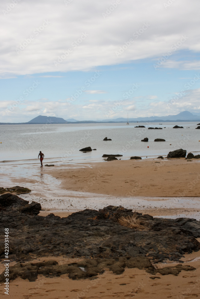 View of the beautiful coastal scenery of Nosy Komba with the quiet beach of Ampangorinana and the mountains of the neighboring island of Nosy Be in the background on the horizon.