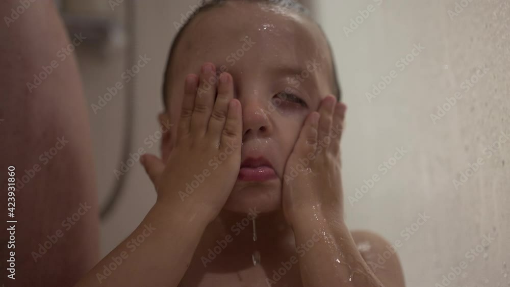 Baby toddler child rubbing face and eyes inside shower bath