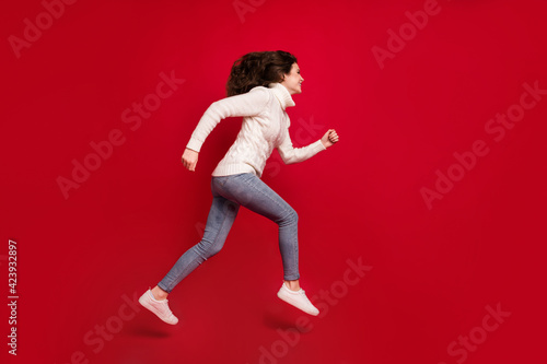 Full length photo of cute purposeful young lady wear collar pullover jumping high running isolated red color background © deagreez