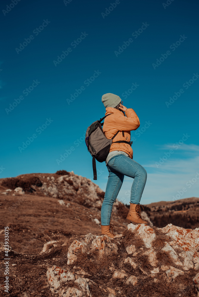 a hiking girl with a backpack on her back watches the morning from the top of the mountain