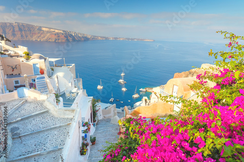 Narrow street with flowers, traditional Greek houses and a staircase to the sea, Santorini, Greece