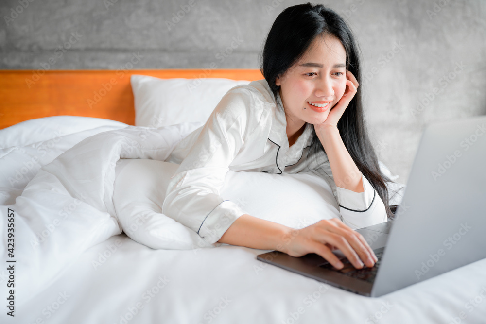 Asian young women portraits Wake up happy from bed She is working in the bedroom Use the laptop computer while working after waking up. Asian young women portraits Wake up happy from bed She is working in the bedroom Use the laptop computer while working after waking up.
